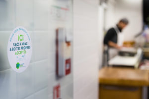 Un autocollant "Contenants personnels acceptés" sur la porte d'un commerce.